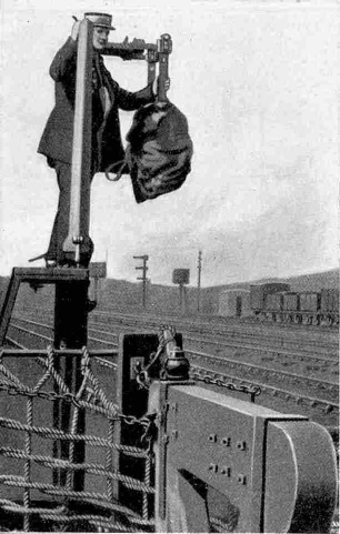 Postman fixing a pouch in position to be picked up by the mail train.