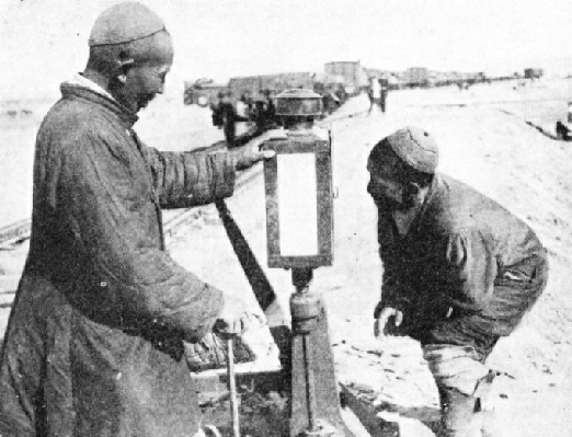 ASIATIC RAILWAY WORKERS examining the points on a stretch of track in Manchuria.